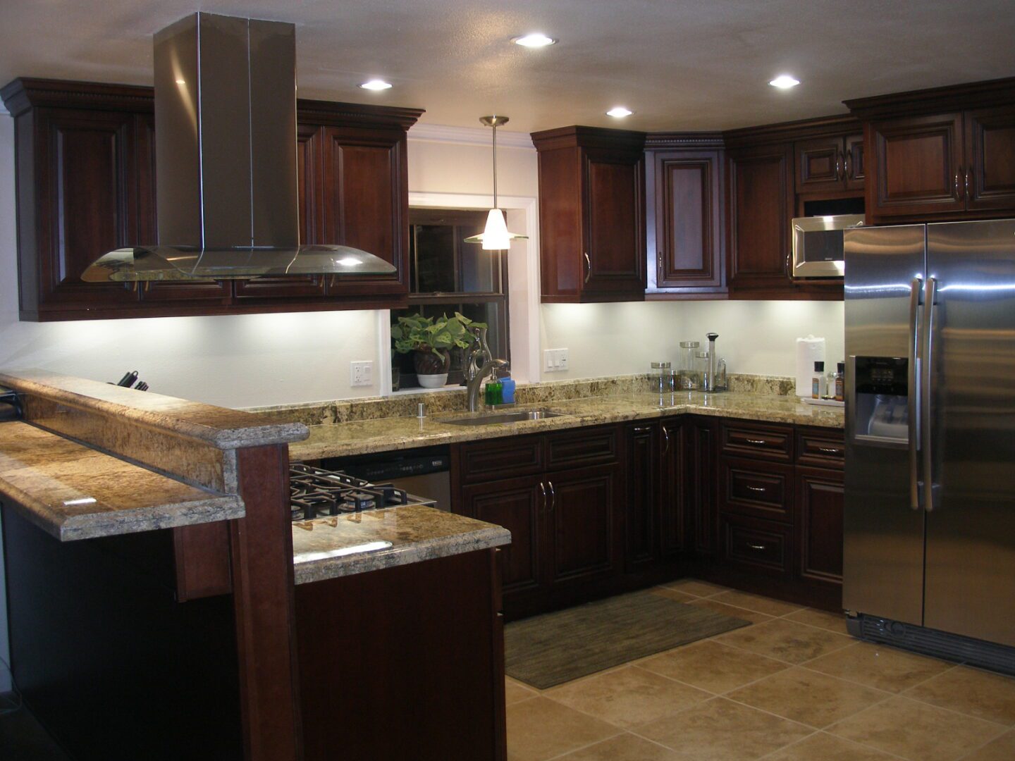 A kitchen with dark wood cabinets and granite counter tops.