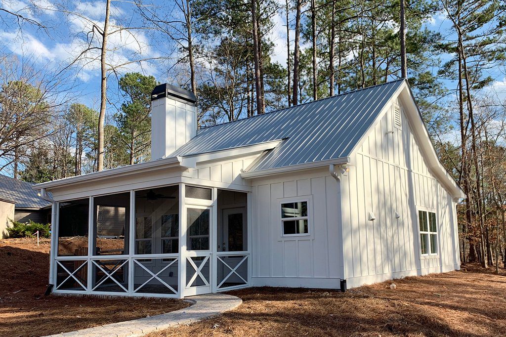 A white house with a porch and metal roof.